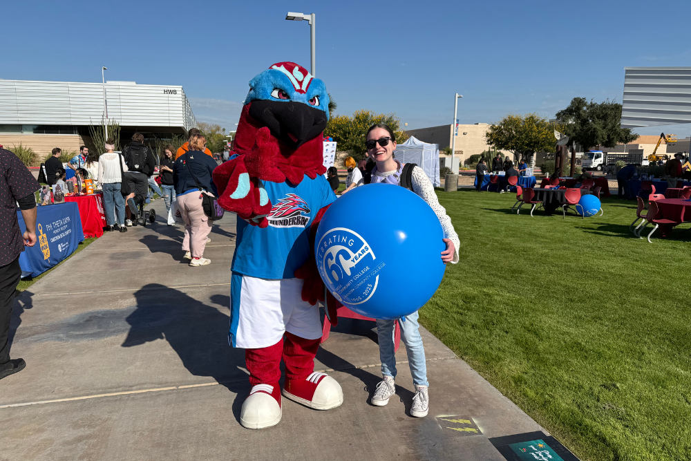 Student posing with mascot Thor the Thunderbird at a festival