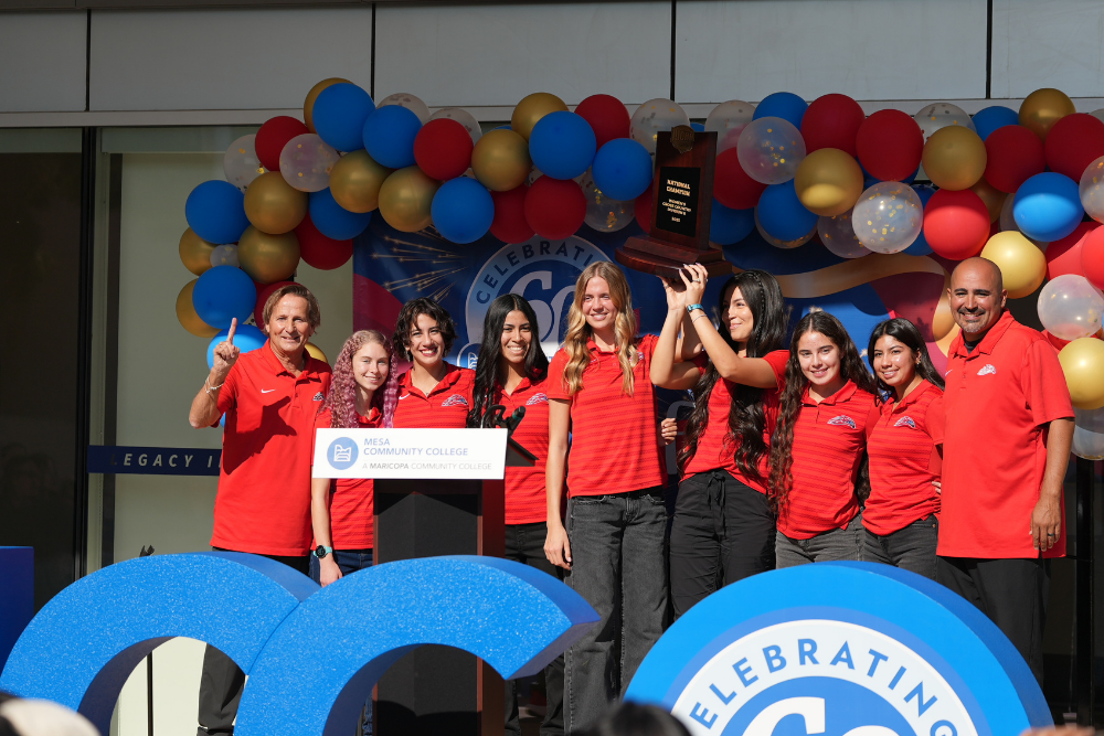 Group of athletes with coach on stage at MCC's 60th anniversary celebration